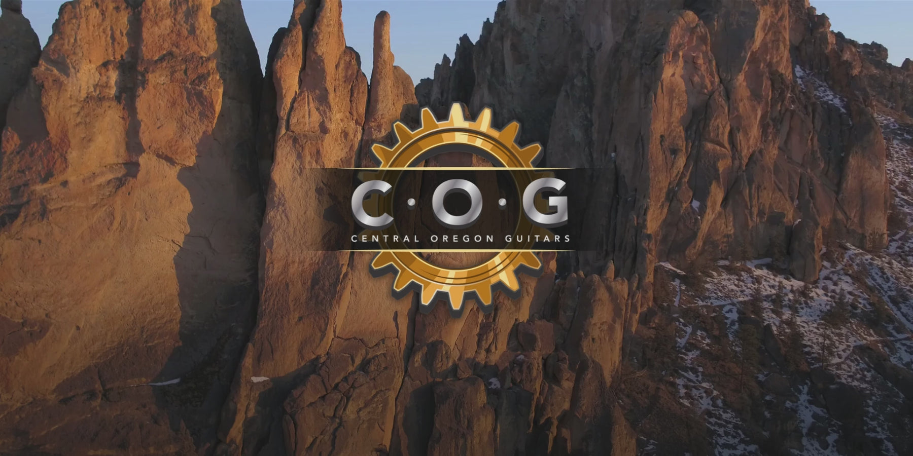A video of Smith Rock State Park with the Central Oregon Guitars logo slowly spinning in the center. There are 6 guitars that slowly come into focus, 3 on each side. There is solo electric guitar music playing in the background.